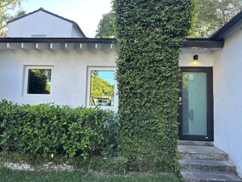 Glass impact entry door with a black frame on a Coral Gables home