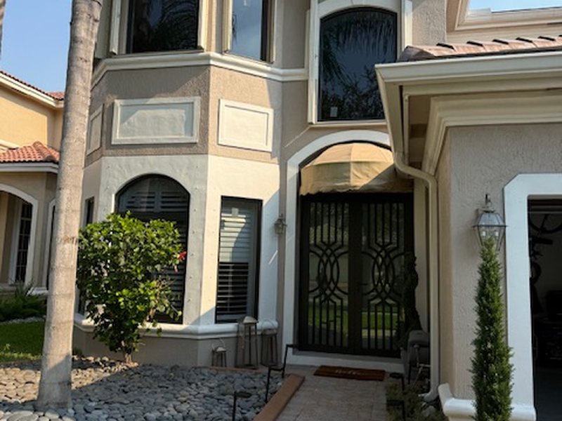 Decorative iron-and-glass impact double entry doors on a two-story Miramar home