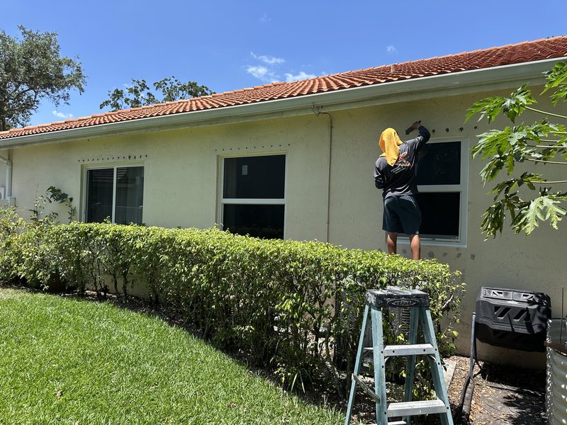 A Hurricane Pros installer fitting a new impact window on a tile-roof home in Pembroke Pines